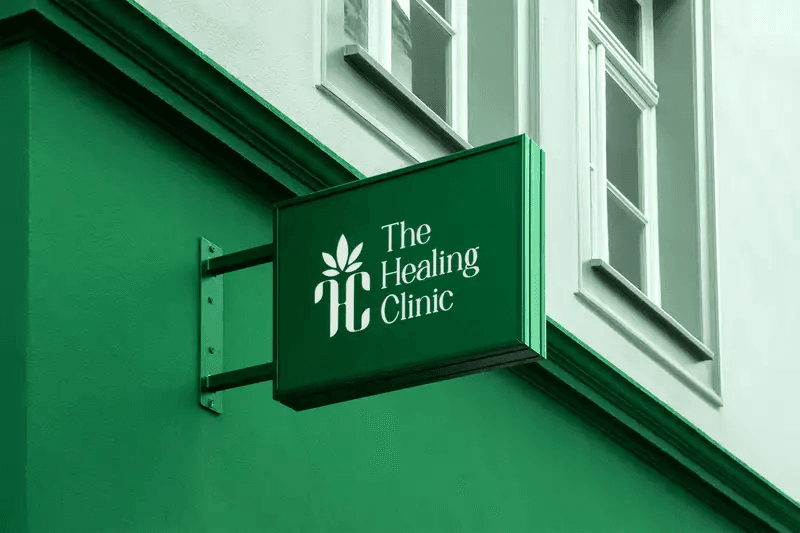 A green hanging rectangular sign for The Healing Clinic on a matching green wall.