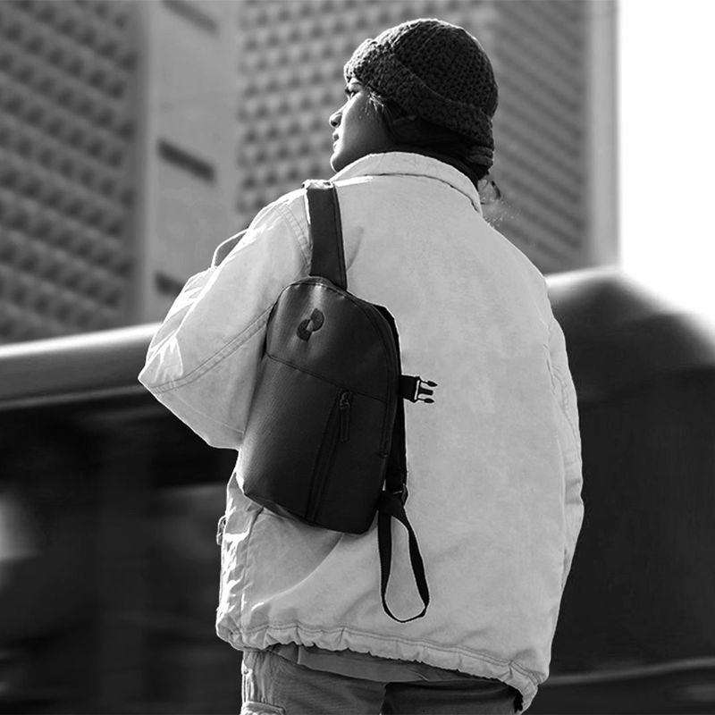Black and white photo of a person wearing a beanie and a small backpack.