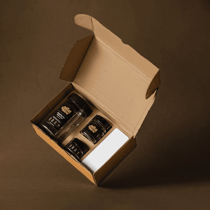 Open cardboard box containing three labeled tea jars and a white gift card.