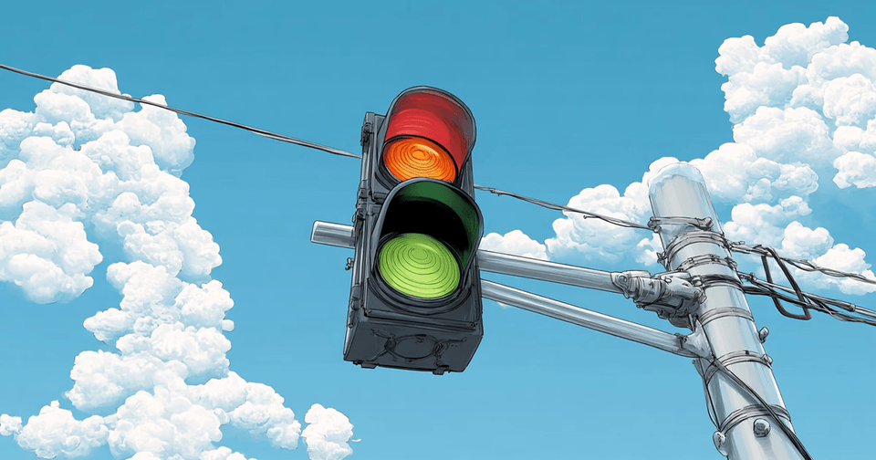 A traffic signal with glowing amber and green lights hangs against a cloud-filled blue sky.